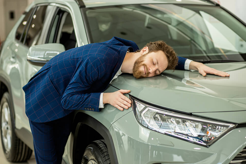 mann som gir klem til bilen sin